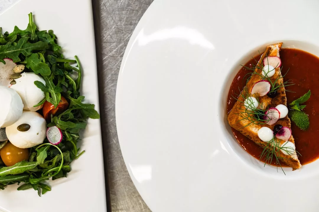 Experience a taste of luxury resorts with this plated salad featuring mozzarella, tomatoes, arugula, and a bowl of tomato soup with bread and herbs—perfect before exploring Magaluf's boutique dessert restaurants.