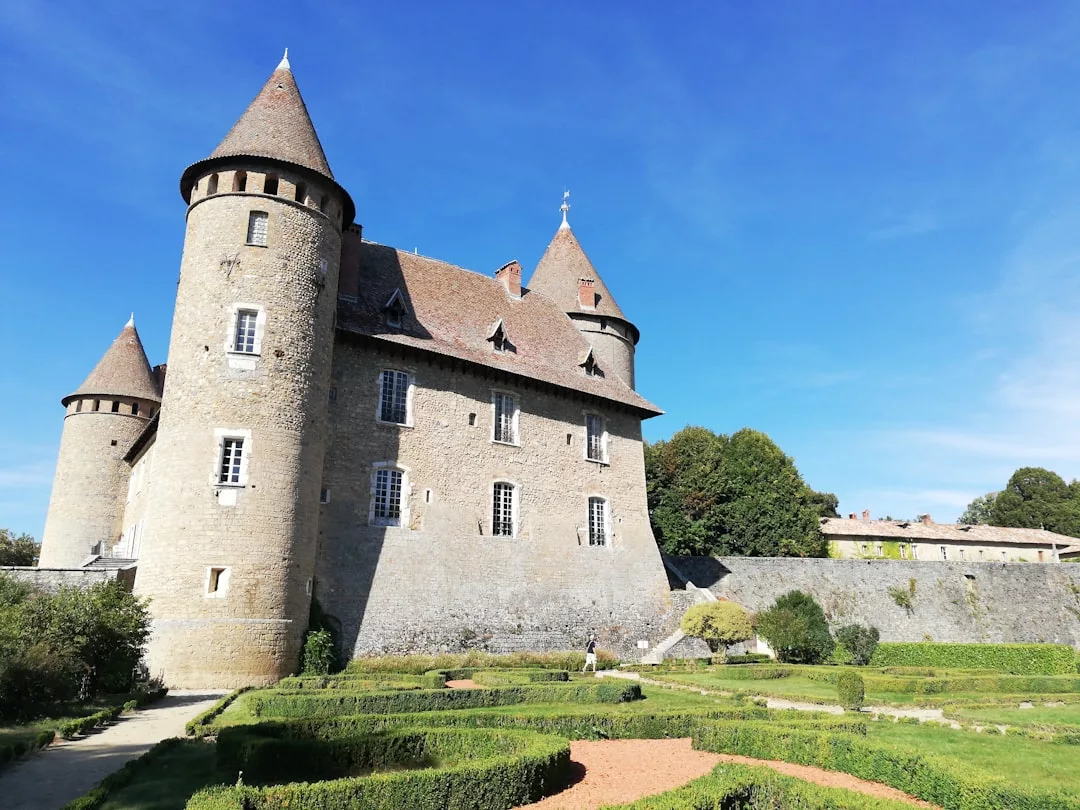 Medieval stone castle with conical towers and a manicured chef’s garden, perfect for tours before dining in Son Servera under a clear blue sky.