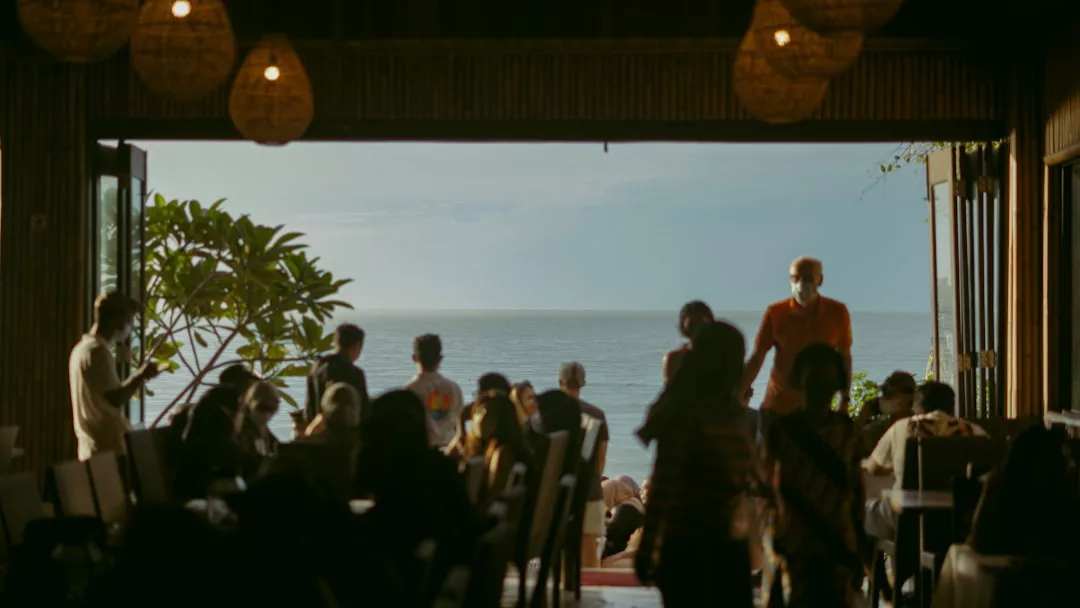 People dining in a restaurant with an open view of the ocean and trees in the background during daylight, enjoying the relaxed atmosphere that Santa Ponsa is known for.