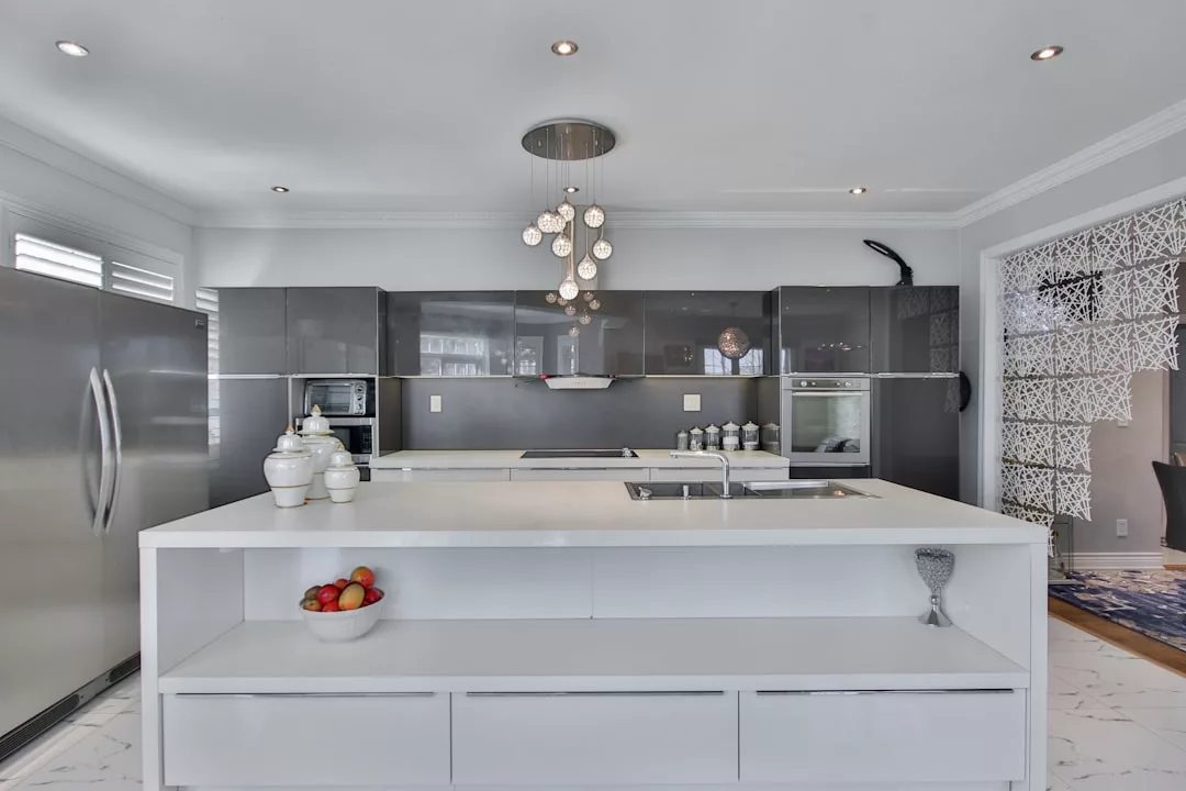 Modern kitchen with glossy cabinets, a large white island, pendant lights, and stainless steel appliances—ideal for hosting Michelin-level culinary workshops in the heart of Port d’Andratx.