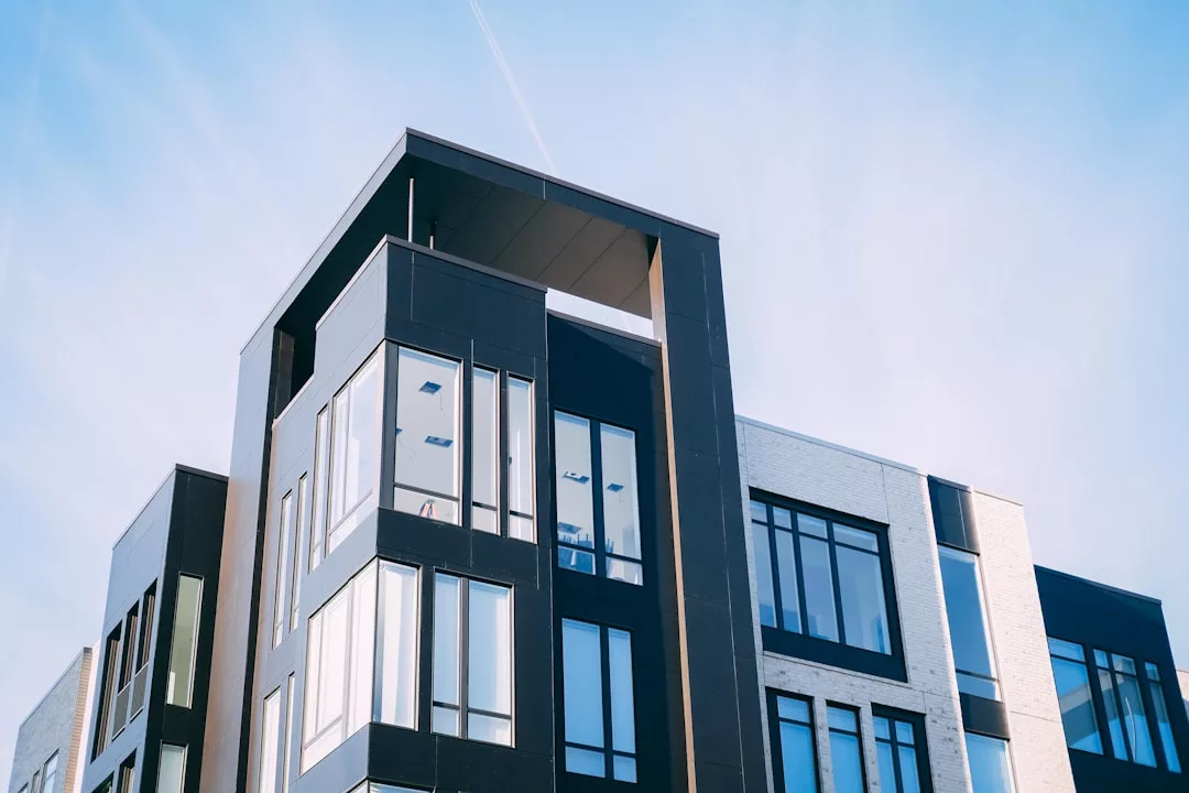 Modern apartment building with large windows and geometric architecture against a clear blue sky, ideal for student accommodation near Palma University—an excellent investing opportunity.