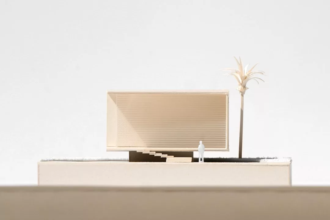 Minimalist architectural model with a box-shaped building, a small figure, stairs, and a palm tree on the right—evoking the serene vibe of Mallorca’s luxury apothecaries.