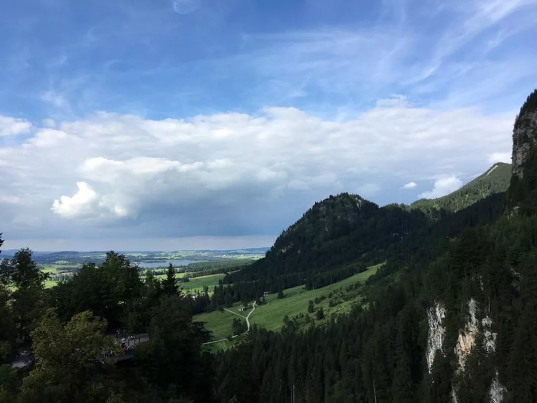 Mountain landscape with green hills, dense forest, and a partly cloudy blue sky above—perfect for luxury day trips along insider routes near Deià.