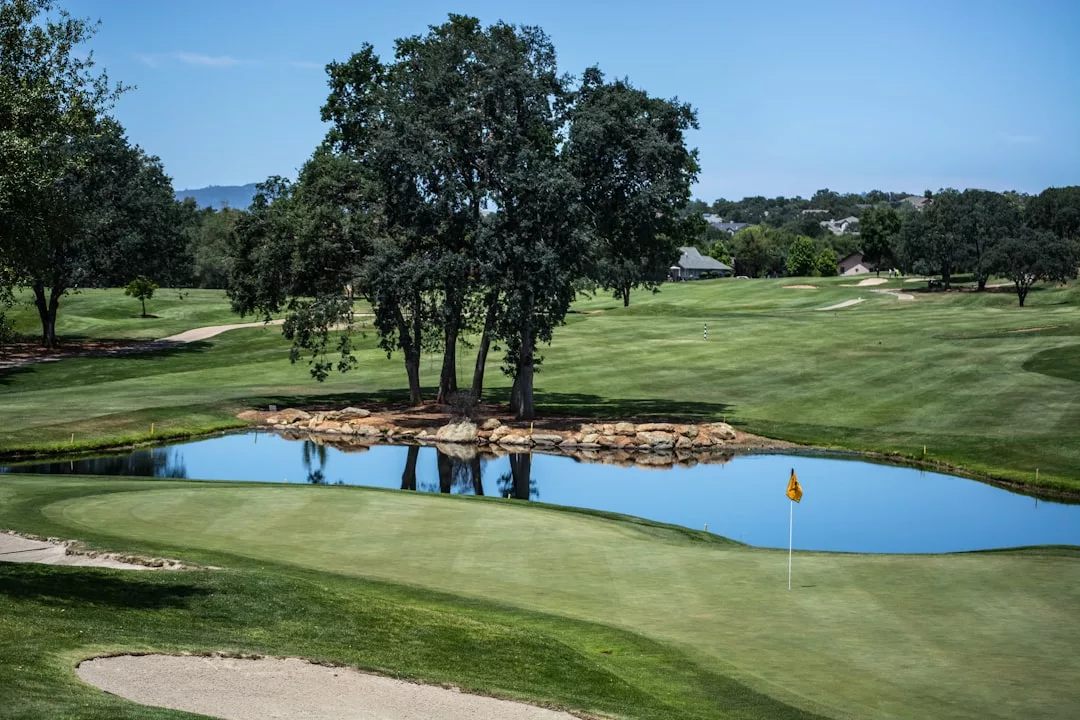 A golf course in Santa Ponsa with a green, sand trap, pond, trees, and distant houses under a clear blue sky—one of the premier golf resorts on the southwest coast.