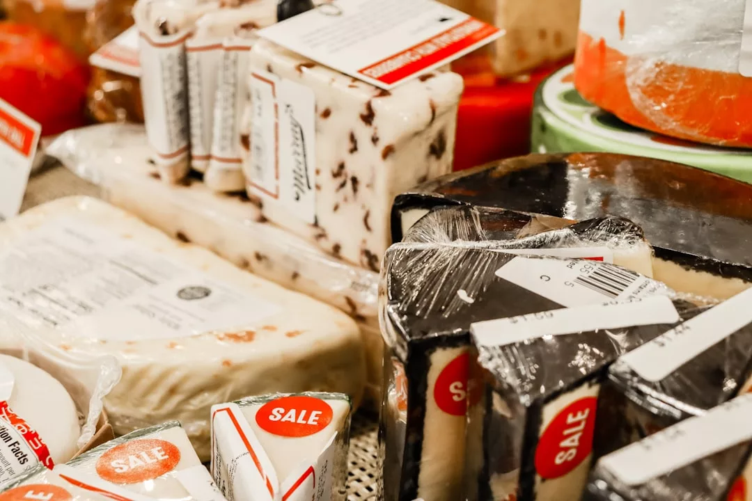 Assorted packaged cheeses on display, some with "SALE" stickers, reminiscent of fine dining selections you'd find on the East Coast, in a grocery store or market.