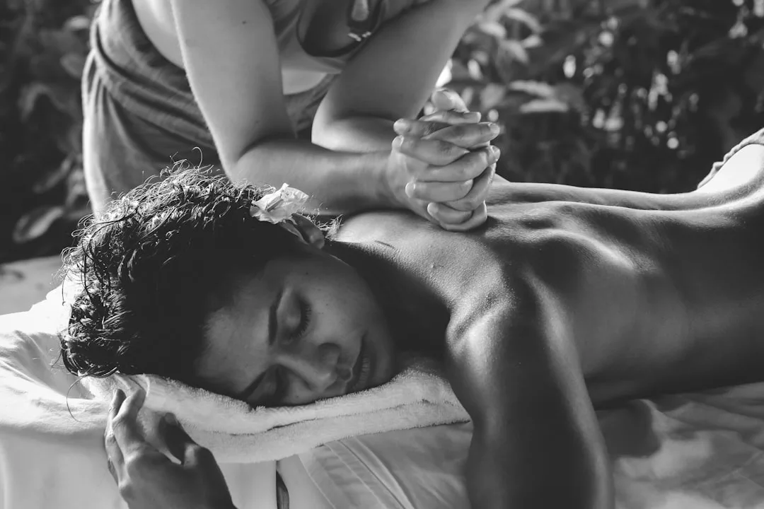 Person lying face down receiving a back massage, eyes closed, in a relaxing outdoor setting nestled in the tranquil mountain village of Valldemossa, perfect for those seeking private spa retreats.
