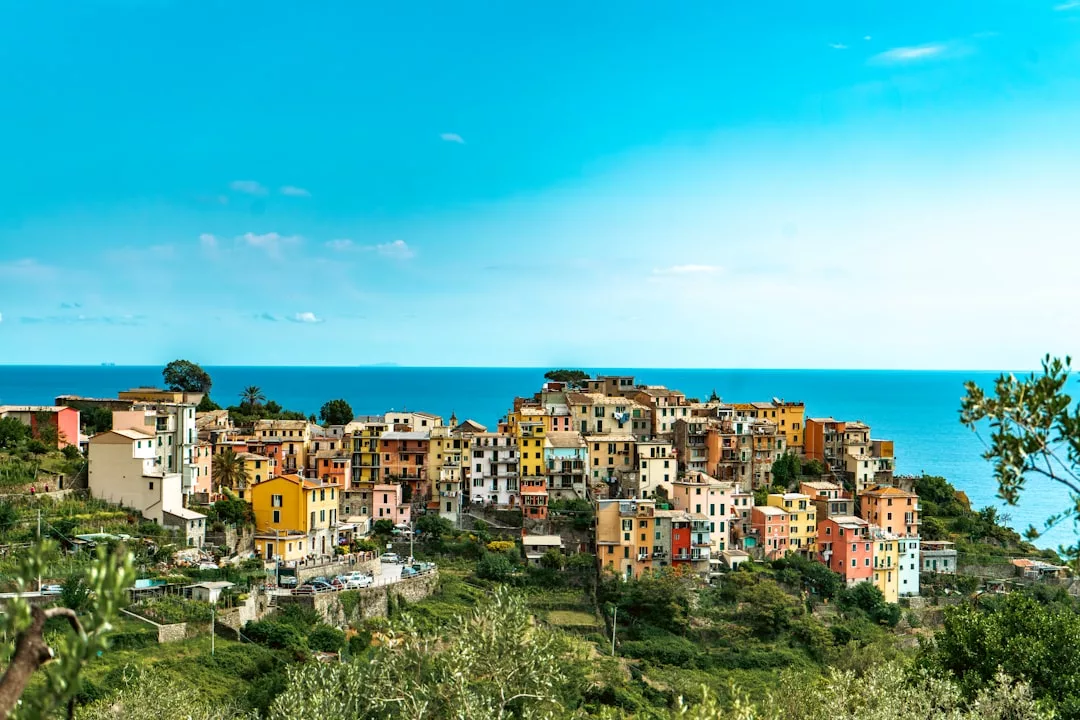 Colorful hillside village of Deià overlooking the sea under a bright blue sky, with green vegetation in the foreground and charming cliffside eateries perfect for romantic sunset dinners.
