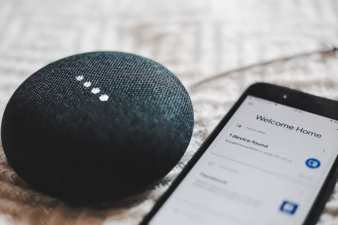 A Google Home smart speaker next to a smartphone displaying a device setup screen, showcasing smart home integration and the latest new developments Alcúdia has to offer.