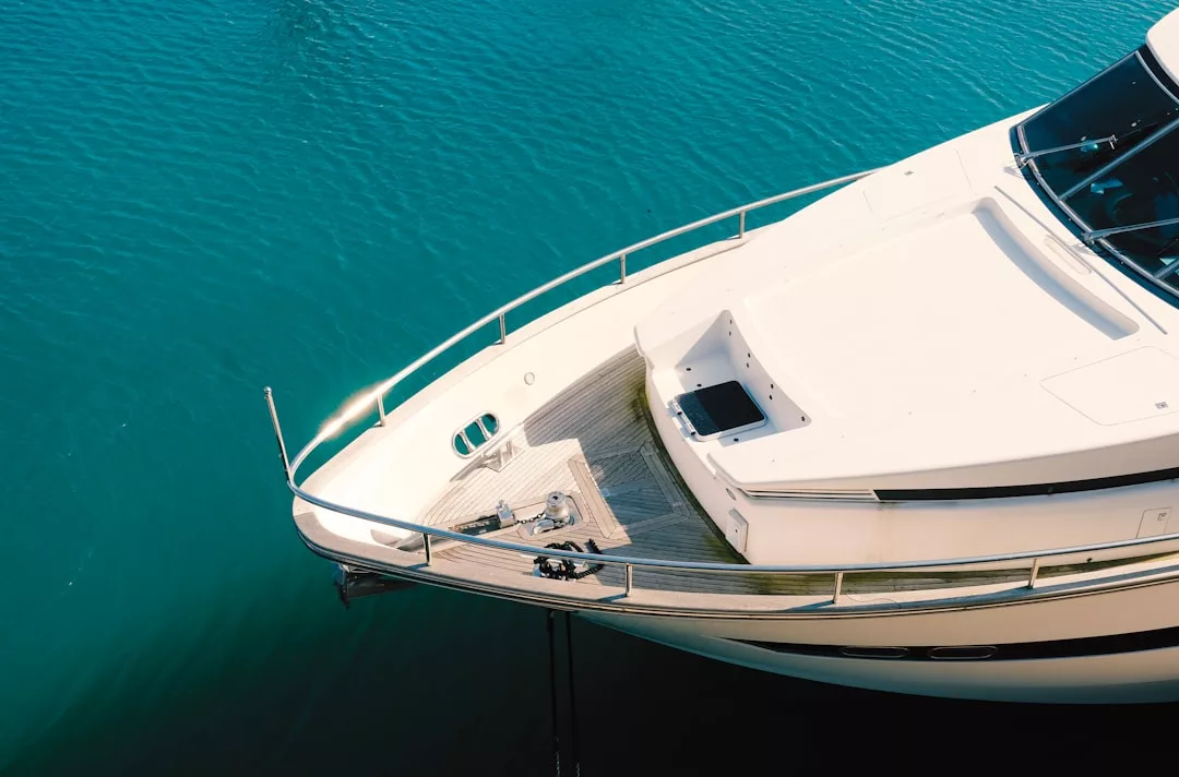 Aerial view of the bow of a white luxury yacht floating on clear blue water in Majorca, showcasing the deck, railing, and anchor equipment—perfect for a refined lifestyle at sea.