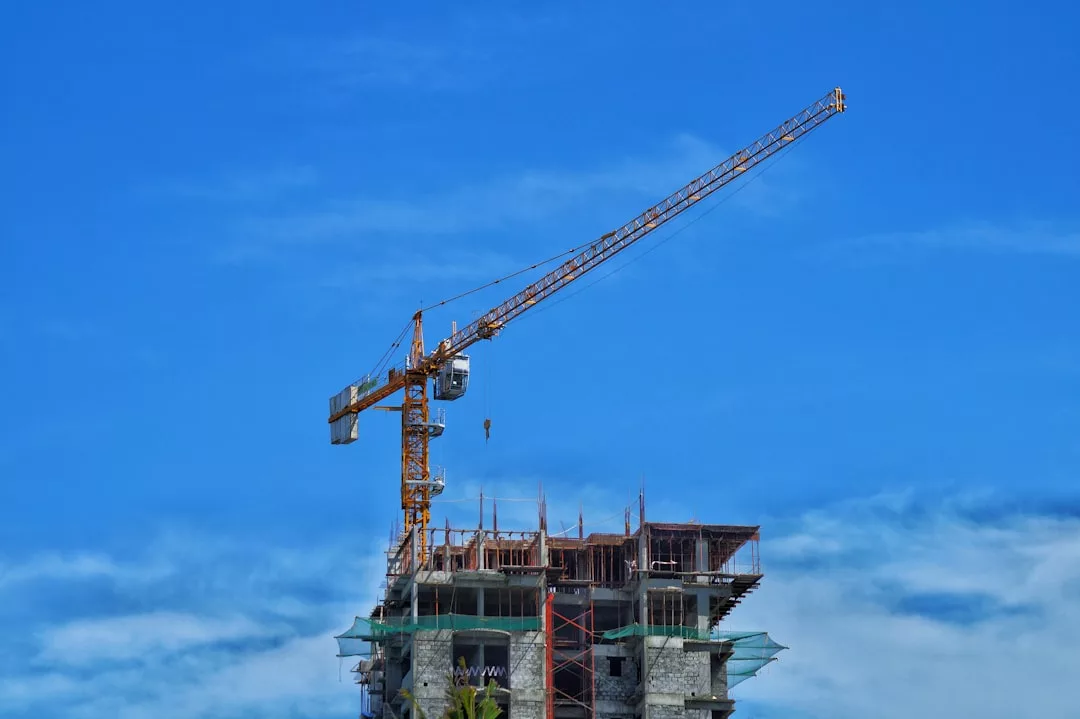A tower crane stands above a partially constructed luxury building with scaffolding, set against Majorca’s clear blue sky.