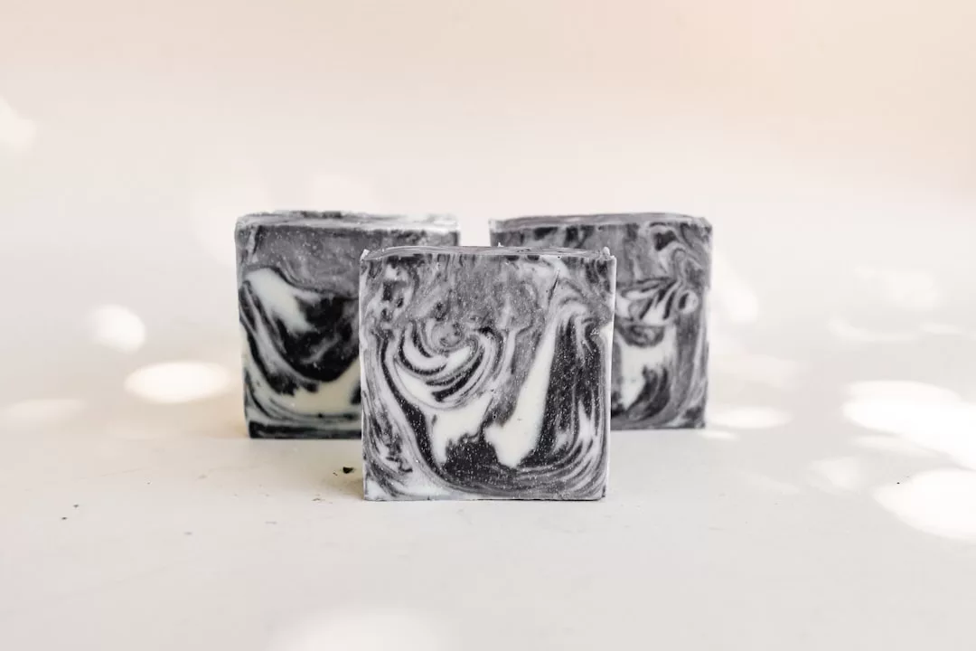 Three square bars of black and white marbled soap evoke a sense of luxury, displayed on a light surface with soft, diffuse lighting.