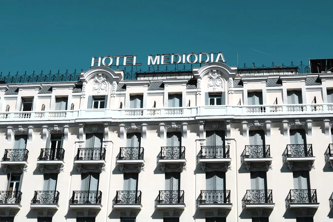 The ornate facade of Hotel Mediodia in Majorca, with balconies and decorative architectural details under a clear blue sky, embodies luxury and refined lifestyle.