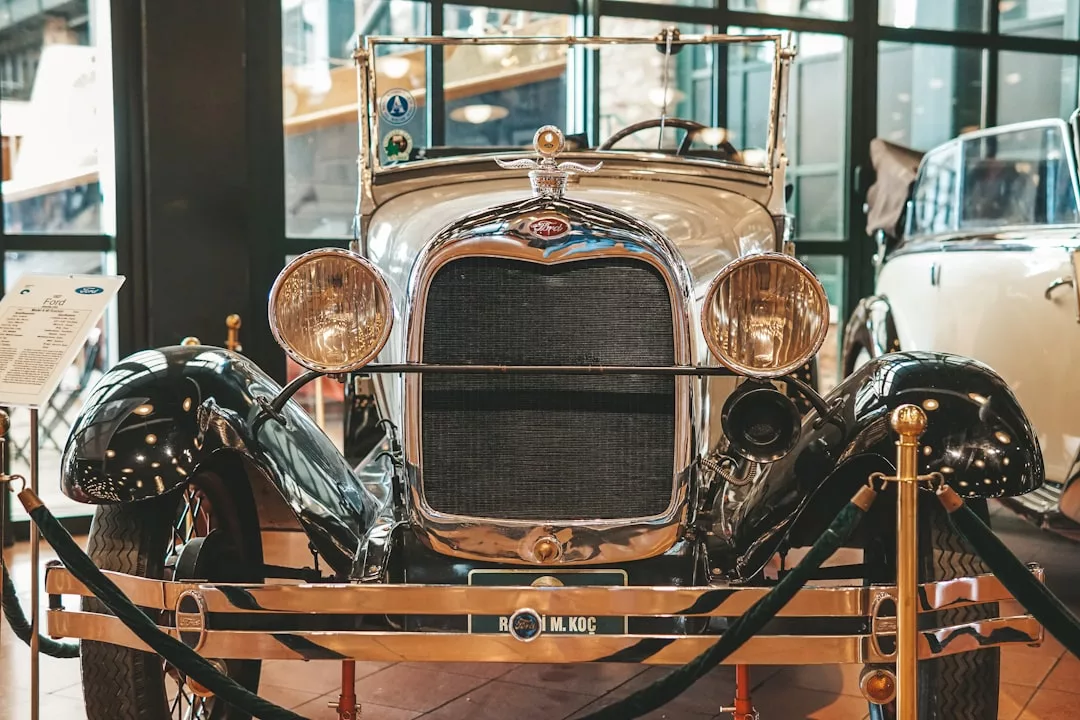 Front view of a luxury vintage car with a chrome grille and round headlights, displayed indoors behind ropes at an exhibition—an iconic lifestyle statement reminiscent of Majorca’s elegance.