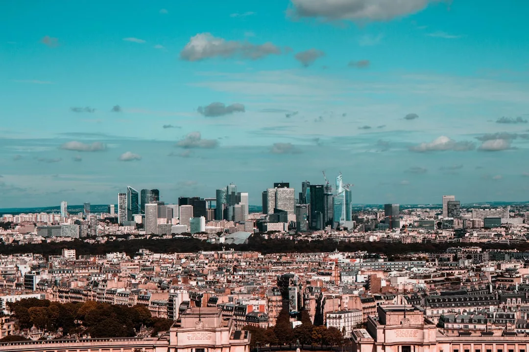 Panoramic view of a city blending historic low-rise buildings in the foreground with modern skyscrapers in the background, capturing the essence of luxury lifestyle under a blue sky with scattered clouds.