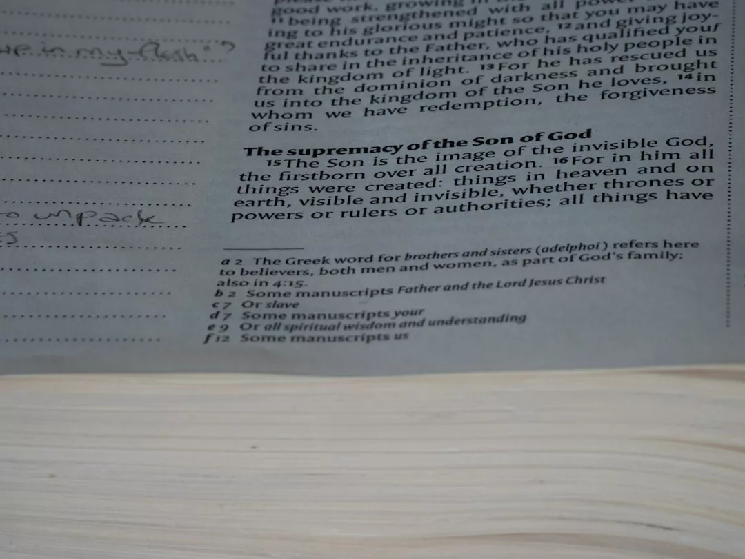 A close-up of a Bible page highlighting Colossians 1:15-17 with related footnotes visible at the bottom—perfect for those who embrace a mindful lifestyle or seek inspiration while relaxing in Majorca.